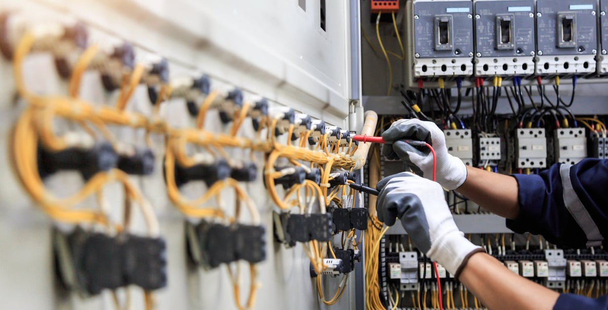 Electricista midiendo corriente en un tablero eléctrico industrial